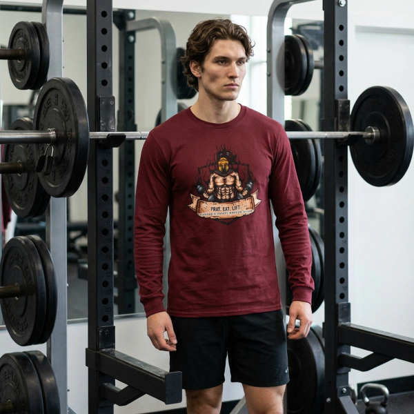 Cardinal red Christian long sleeve shirt featuring a Spartan warrior weightlifting graphic with Pray Eat Lift slogan and Kingdom Mindset Warrior Grind message.